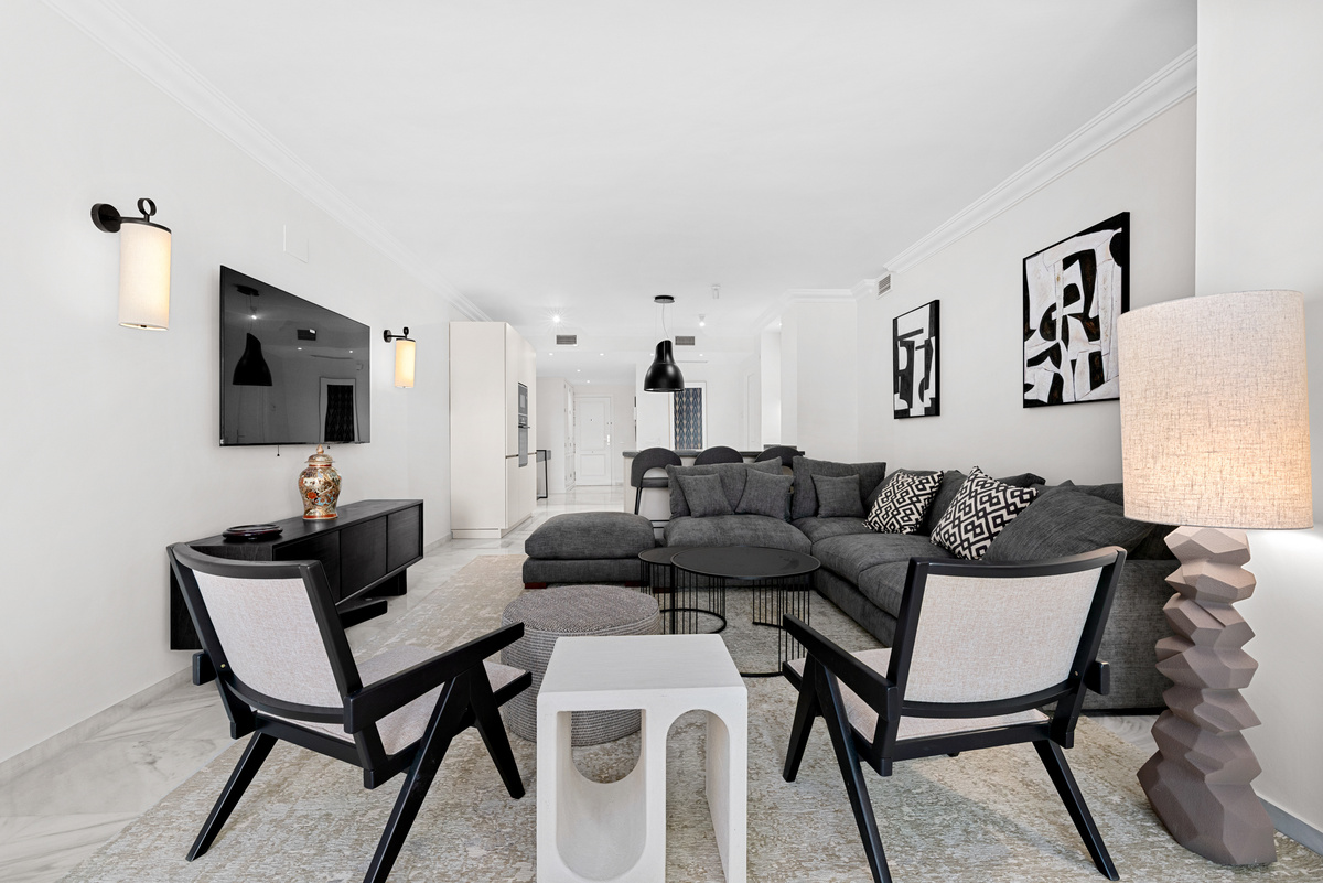 Living area with television and kitchen behind